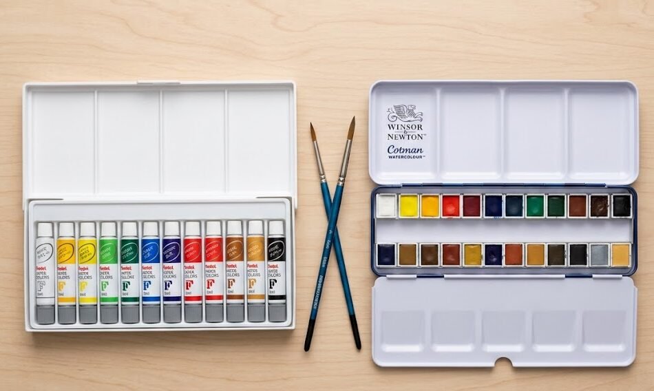 Pentel vs Winsor & Newton: Flat lay comparativo das caixas de aquarela Pentel e Winsor Newton Cotman lado a lado sobre superfície de madeira clara