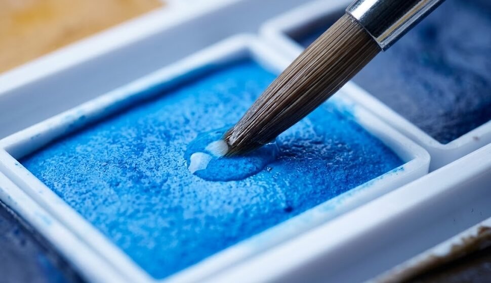 Detalhe das pastilhas de aquarela Winsor Newton Cotman 24 cores com pincel úmido ativando o pigmento azul